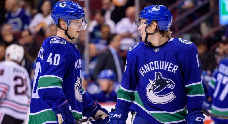 Elias Pettersson and Brock Boeser discuss the situation on the ice.